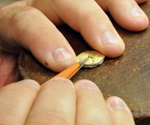 Norman Hege Jewelers | A pair of hands using a tool to do jewelry repair on a watch